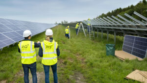 Zwei Personen laufen auf einem Solarpark, während neue Module angebracht werden.